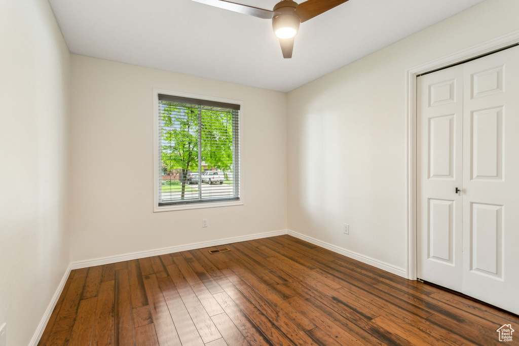 Unfurnished bedroom featuring dark wood finished floors, baseboards, and ceiling fan