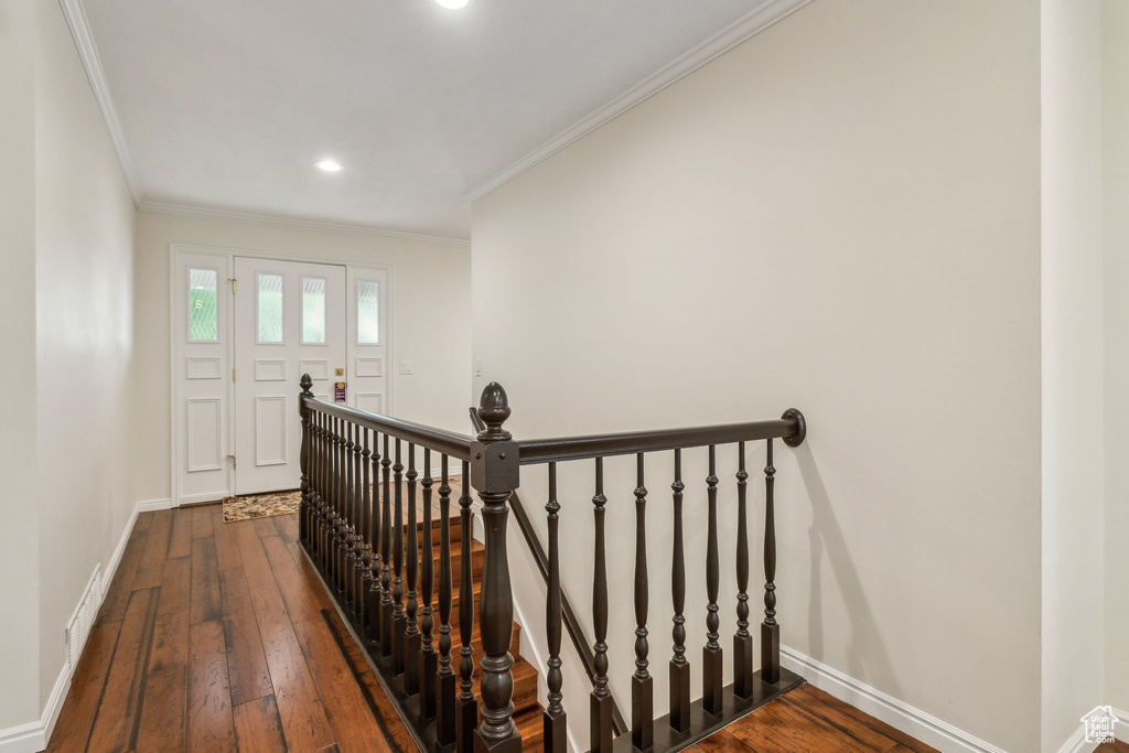 Staircase with baseboards, wood-type flooring, ornamental molding, and recessed lighting