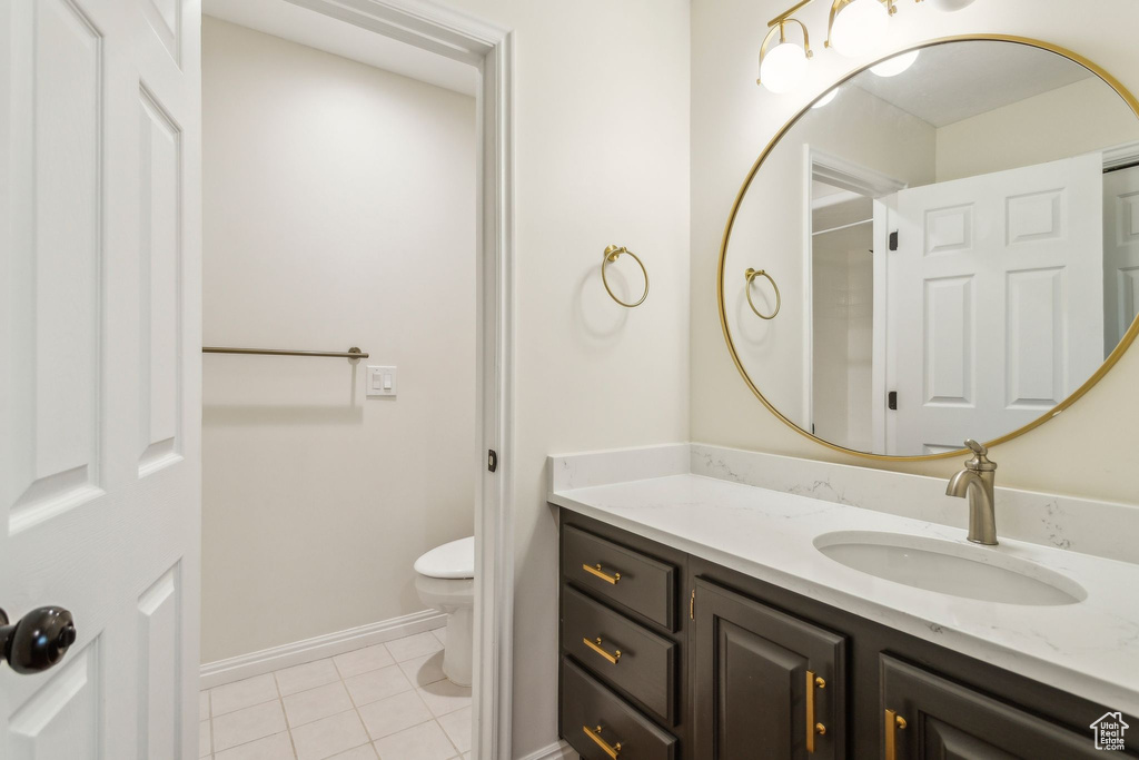 Bathroom featuring toilet, tile patterned floors, vanity, and baseboards