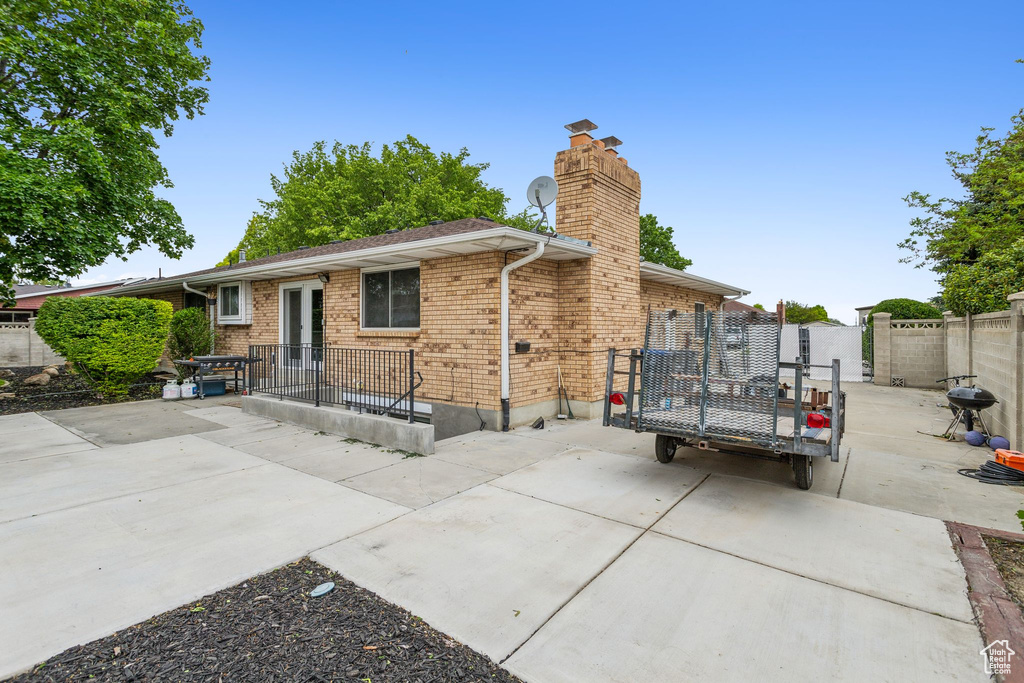 Back of property with a patio area, a chimney, fence, and brick siding