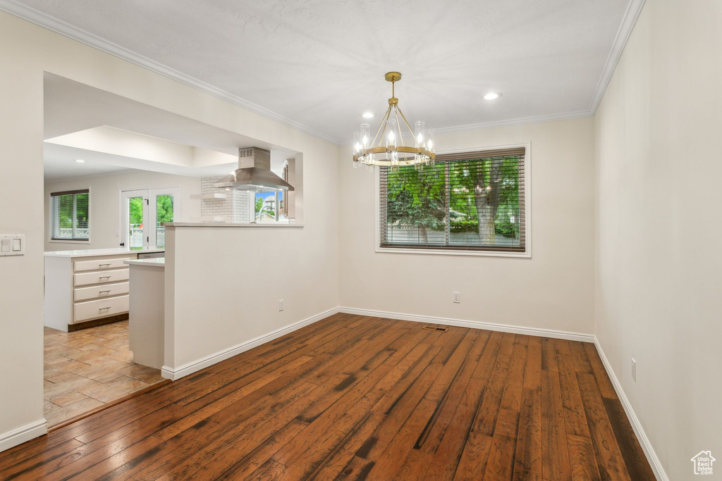 Unfurnished room featuring wood-type flooring, a chandelier, crown molding, baseboards, and recessed lighting