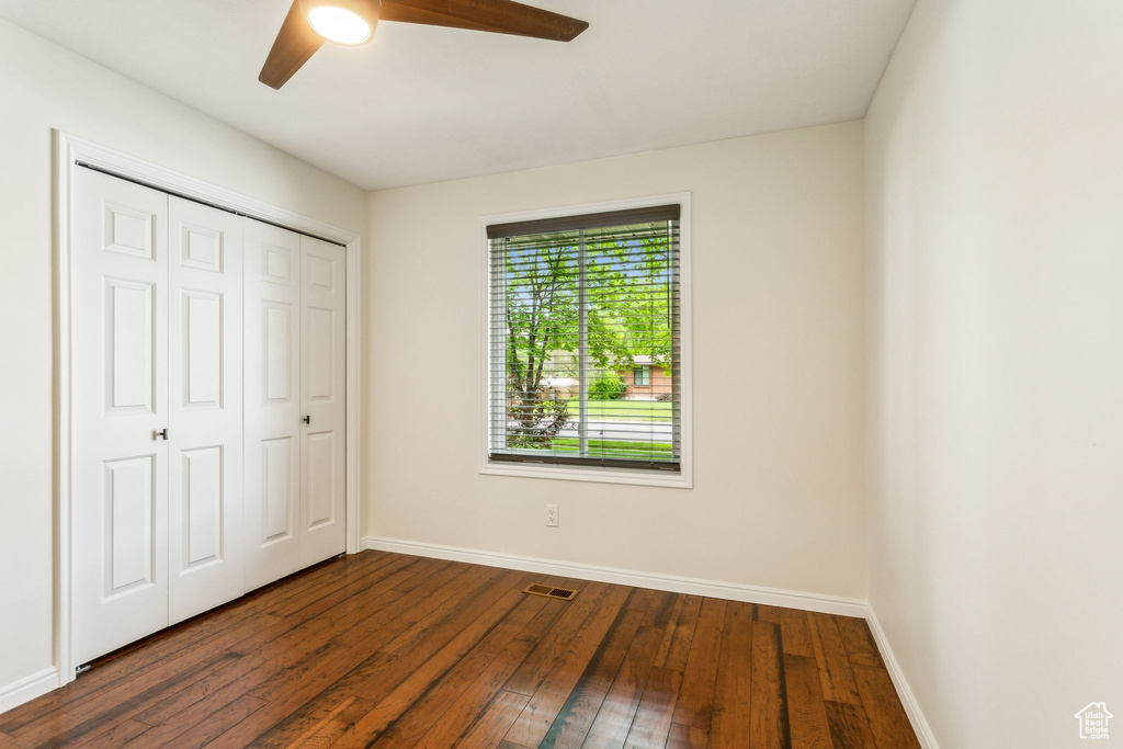Unfurnished bedroom with baseboards, dark wood finished floors, a closet, and ceiling fan