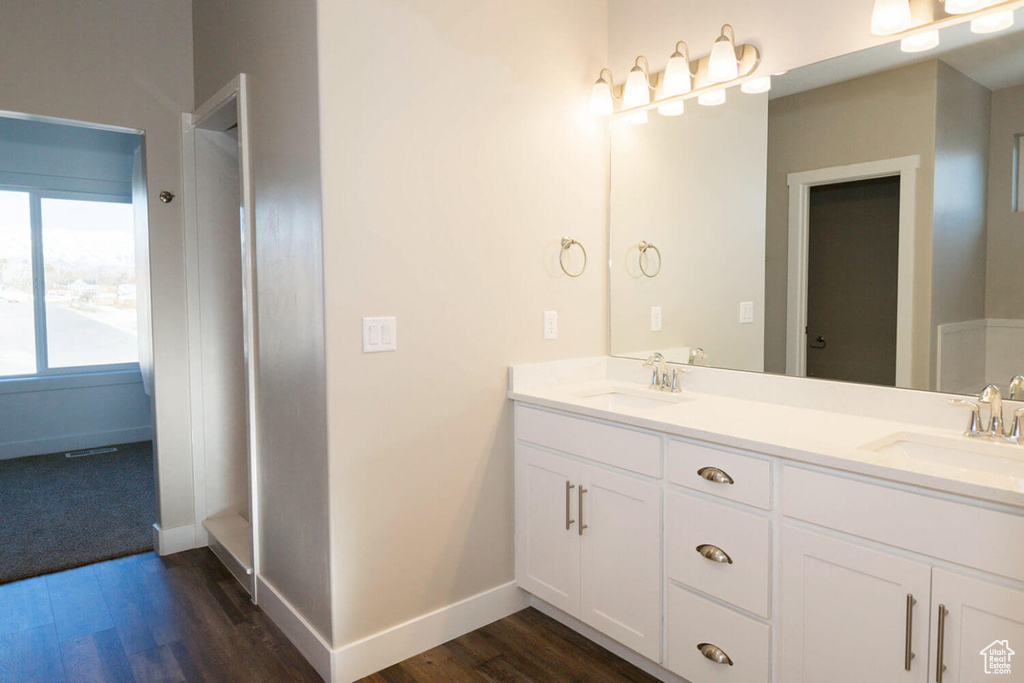 Full bathroom with wood finished floors, double vanity, and baseboards