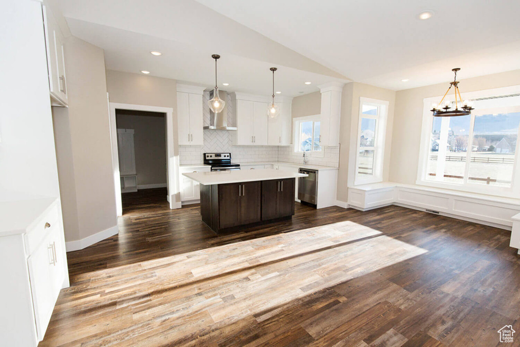 Kitchen with appliances with stainless steel finishes, light countertops, white cabinets, a kitchen island, and decorative backsplash