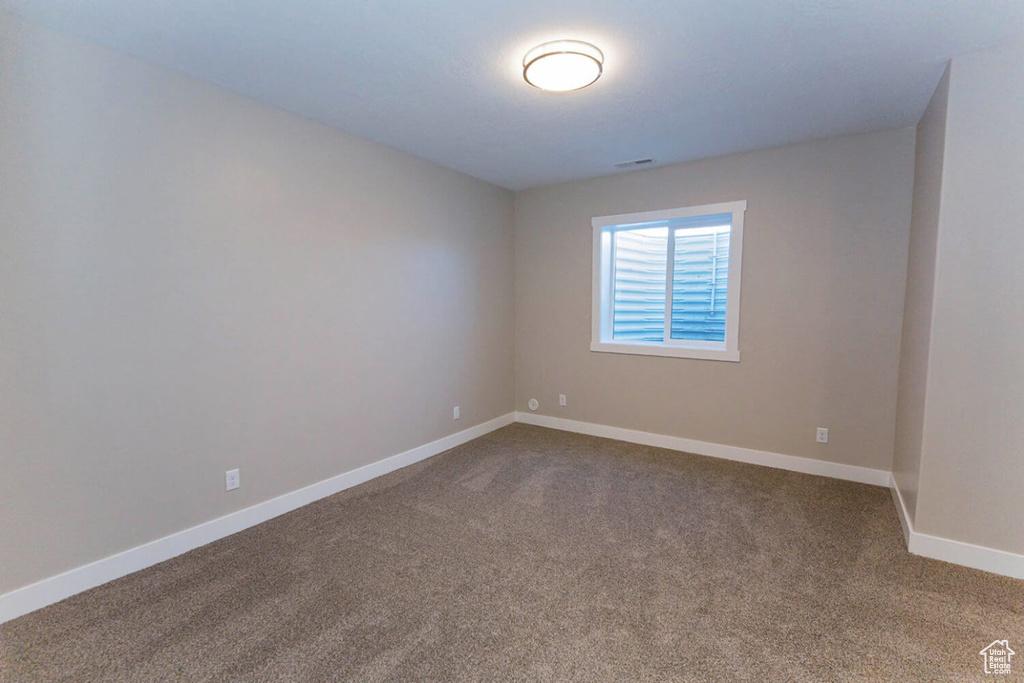 Unfurnished room featuring dark carpet and baseboards