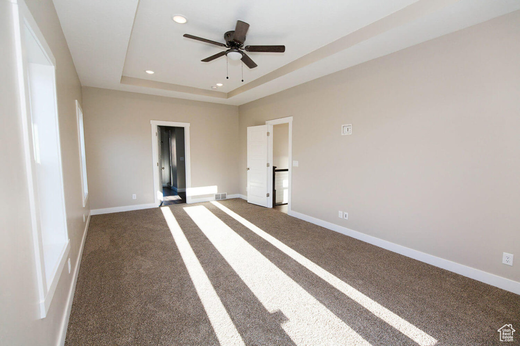 Empty room with carpet, baseboards, a ceiling fan, a raised ceiling, and recessed lighting
