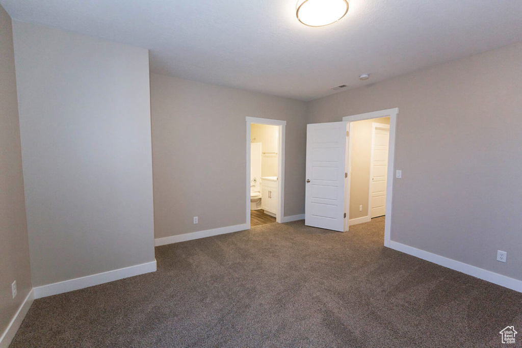 Unfurnished bedroom with carpet, baseboards, and ensuite bathroom