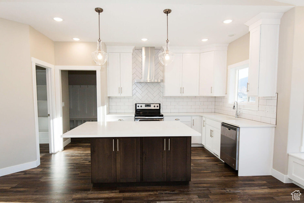 Kitchen with appliances with stainless steel finishes, wall chimney exhaust hood, a sink, light countertops, and tasteful backsplash