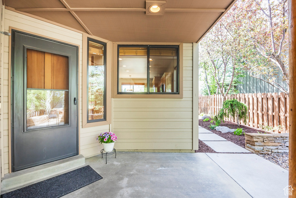 View of exterior entry with fence and a patio area