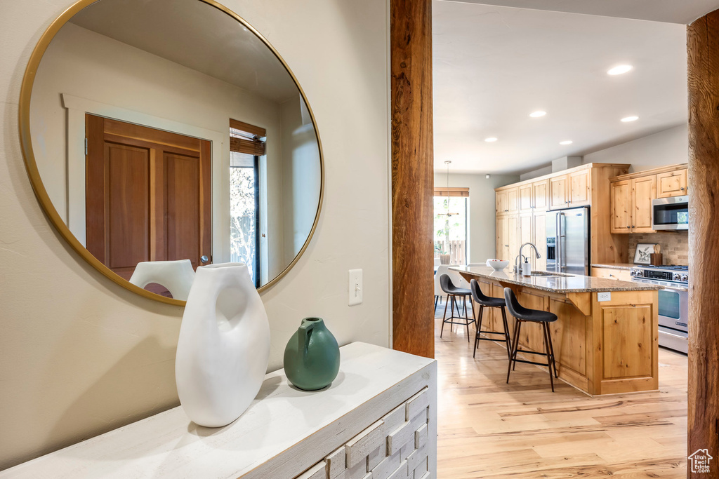 Detailed view of stainless steel appliances, a sink, wood finished floors, and recessed lighting