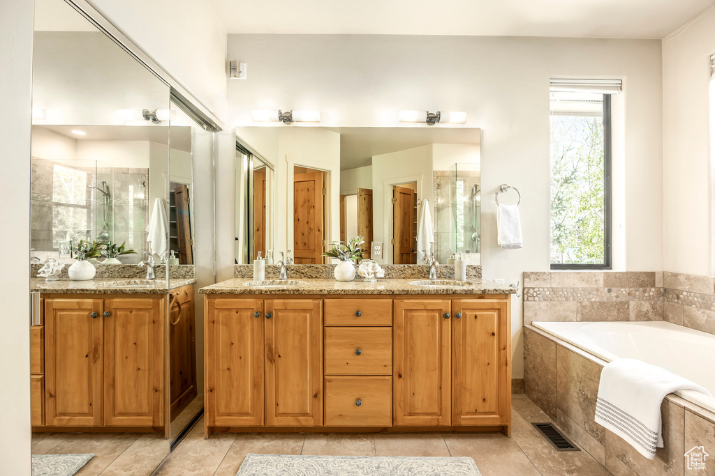 Bathroom featuring a stall shower, a garden tub, double vanity, and tile patterned flooring