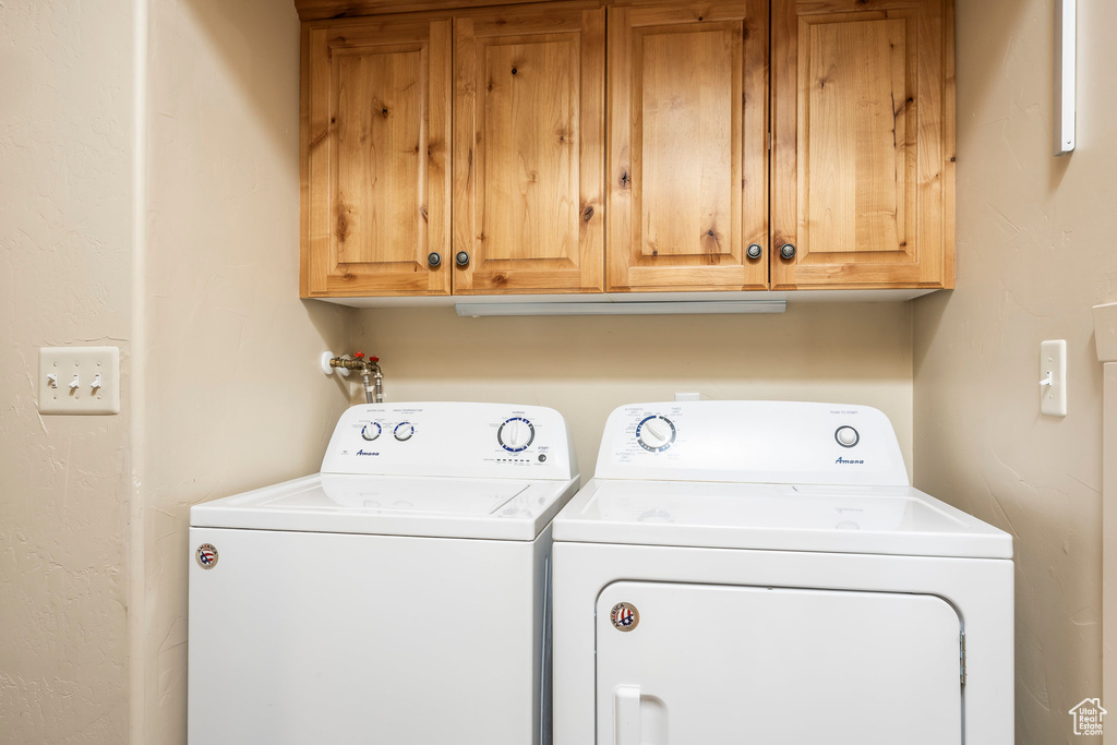 Washroom featuring washing machine and clothes dryer and cabinet space