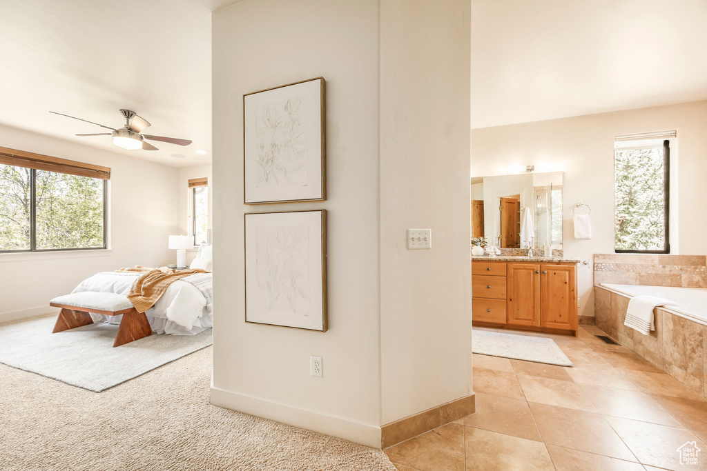 Bedroom with multiple windows, baseboards, light tile patterned floors, and connected bathroom