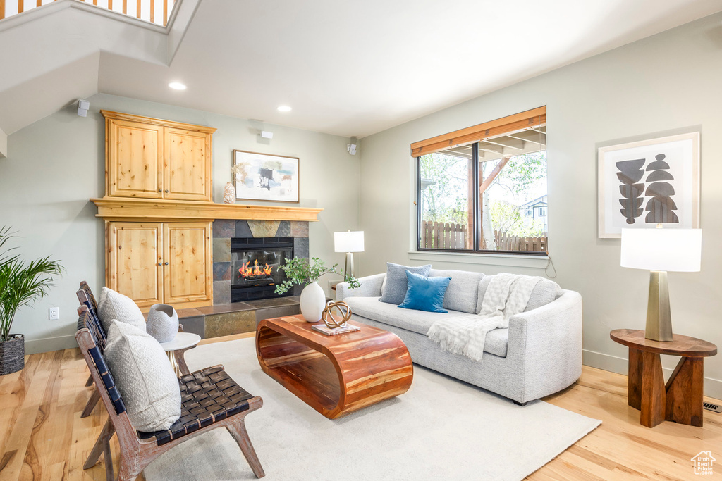 Living room with recessed lighting, light wood-type flooring, baseboards, and a tiled fireplace