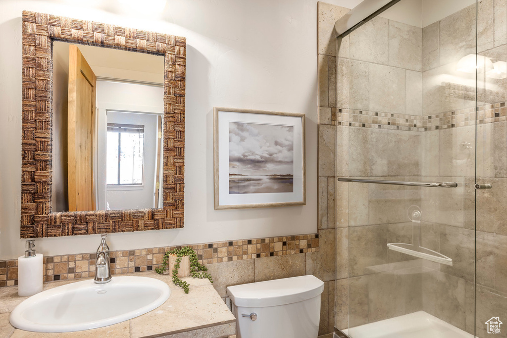 Bathroom with toilet, a shower stall, tile walls, wainscoting, and vanity