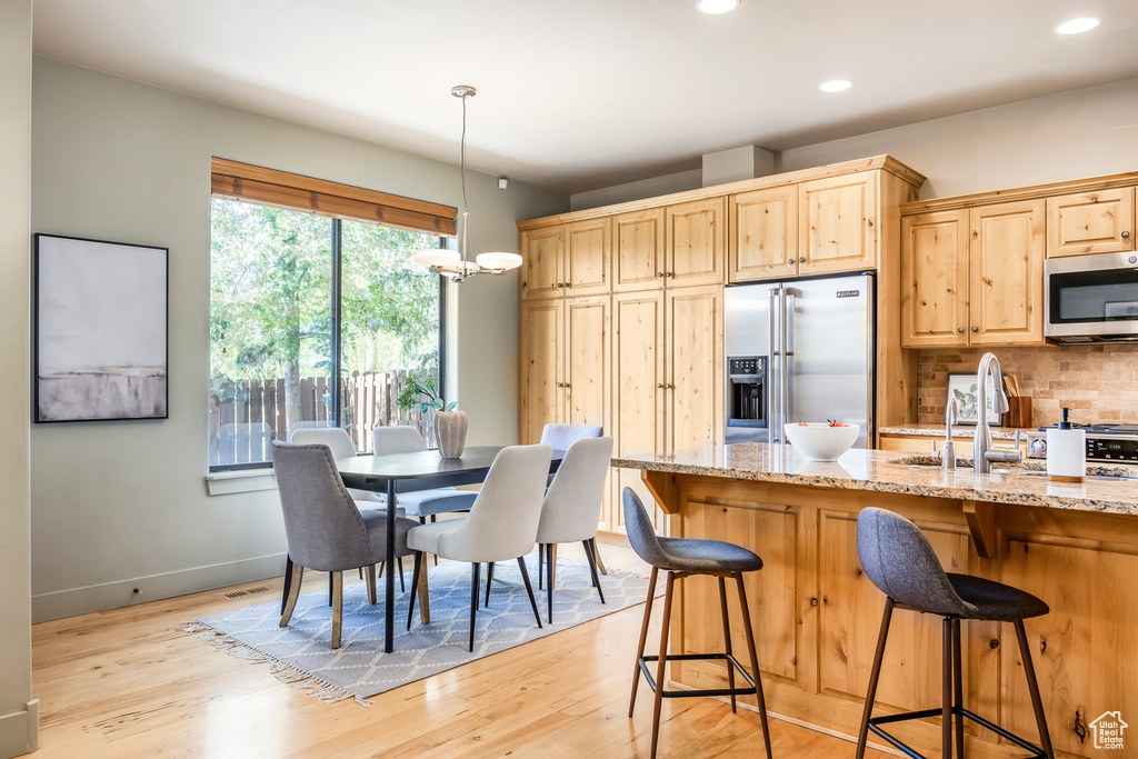 Kitchen with appliances with stainless steel finishes, a sink, light wood-style floors, light stone counters, and recessed lighting