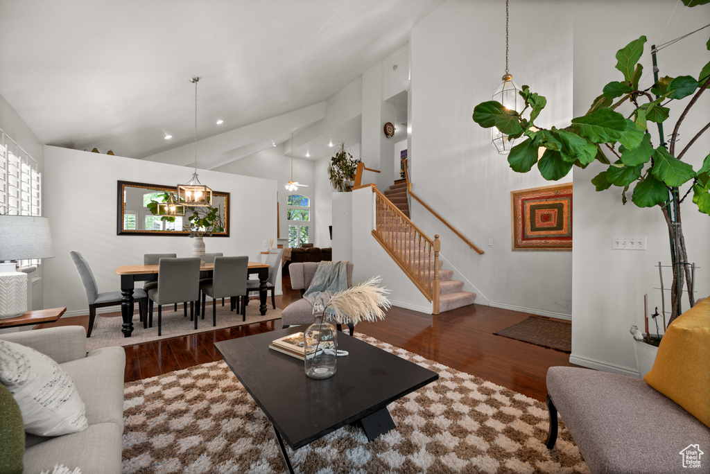 Living area with wood finished floors, stairway, baseboards, high vaulted ceiling, and recessed lighting