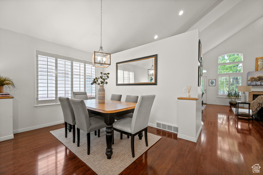 Dining room with a chandelier, vaulted ceiling, wood finished floors, baseboards, and recessed lighting