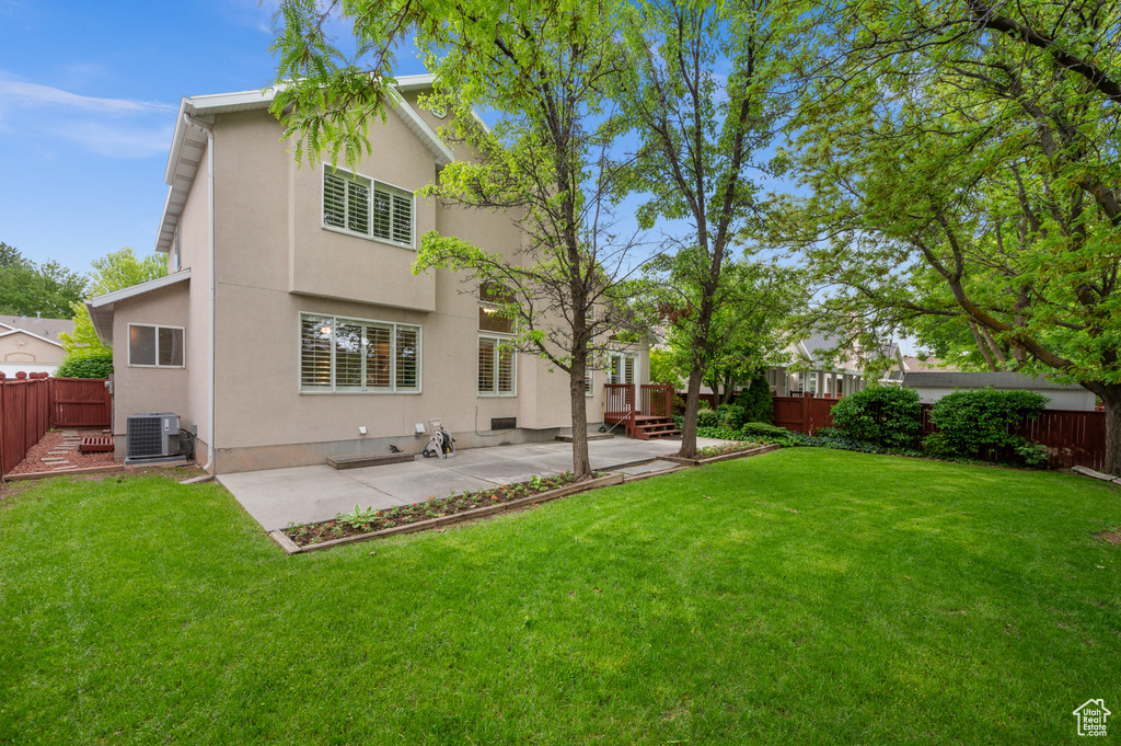 Back of property with stucco siding, central AC unit, and a patio