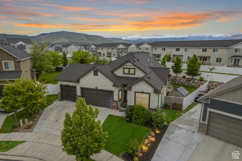 View of front of property with stucco siding, a mountain view, concrete driveway, a residential view, and a shingled roof