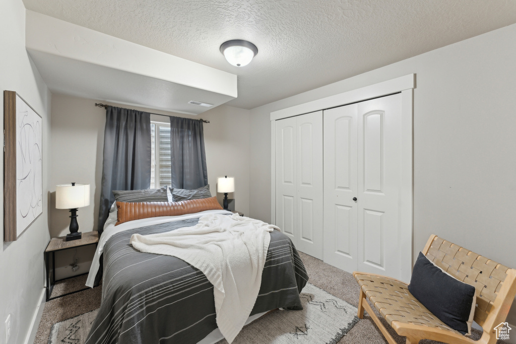 Carpeted bedroom with a closet, a textured ceiling, and baseboards
