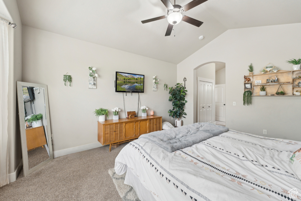 Carpeted bedroom featuring vaulted ceiling, arched walkways, ceiling fan, and baseboards