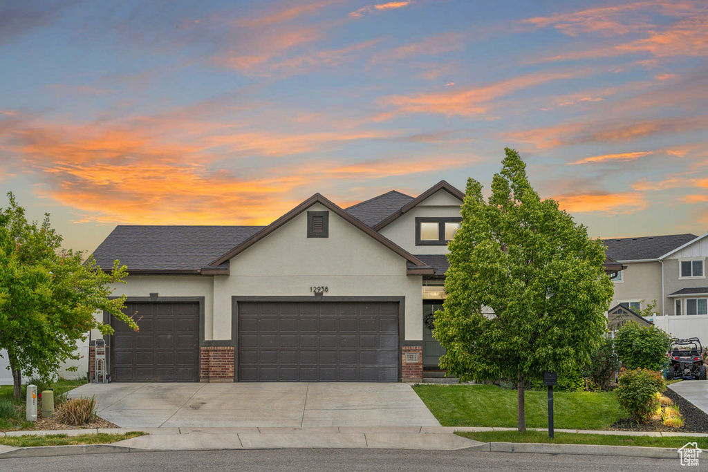 View of front of property with brick siding, concrete driveway, a garage, and stucco siding