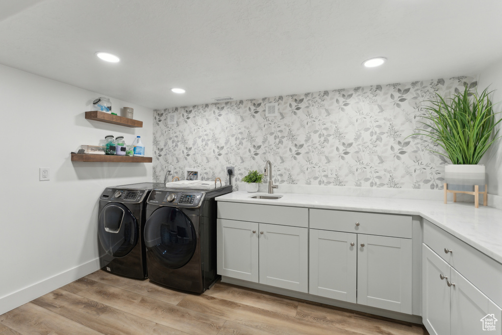 Washroom with separate washer and dryer, recessed lighting, baseboards, light wood-style flooring, and cabinet space