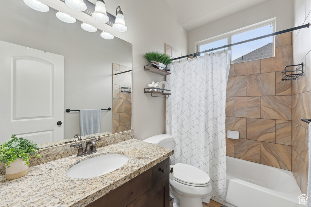 Bathroom featuring toilet, vanity, and shower / bath combo with shower curtain
