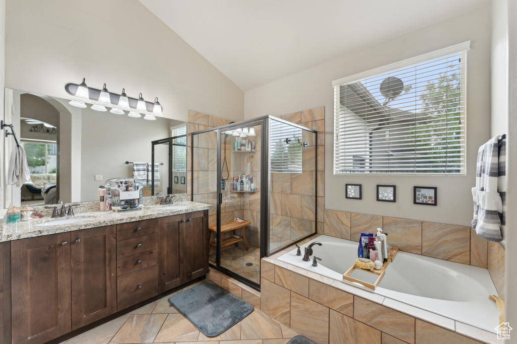 Ensuite bathroom featuring a stall shower, a garden tub, vaulted ceiling, double vanity, and tile patterned flooring