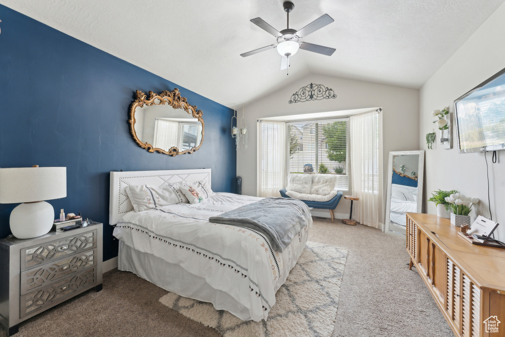 Carpeted bedroom featuring lofted ceiling and a ceiling fan