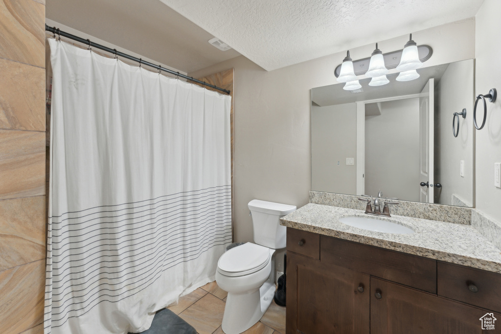 Full bath with a textured ceiling, vanity, toilet, tile patterned flooring, and shower / bath combo with shower curtain