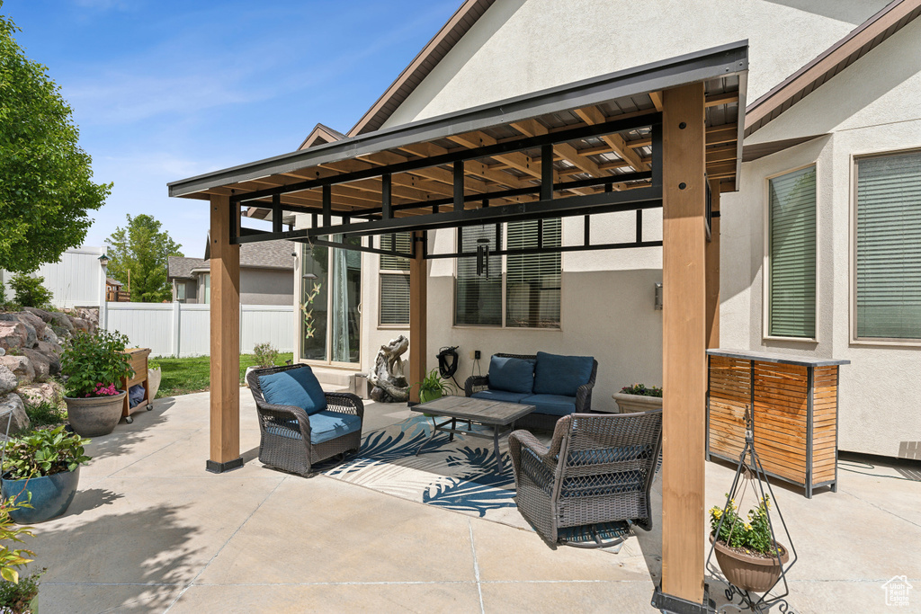 View of patio with an outdoor hangout area and fence