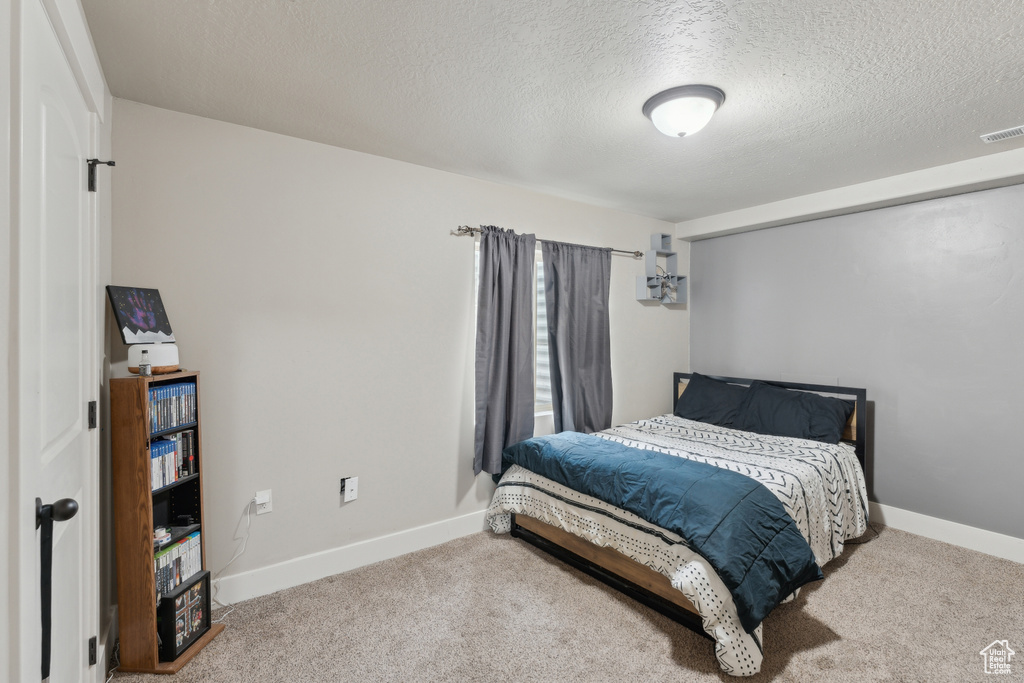 Carpeted bedroom with a textured ceiling and baseboards