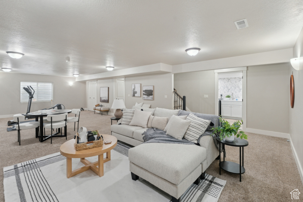 Living area featuring light carpet, stairway, and baseboards