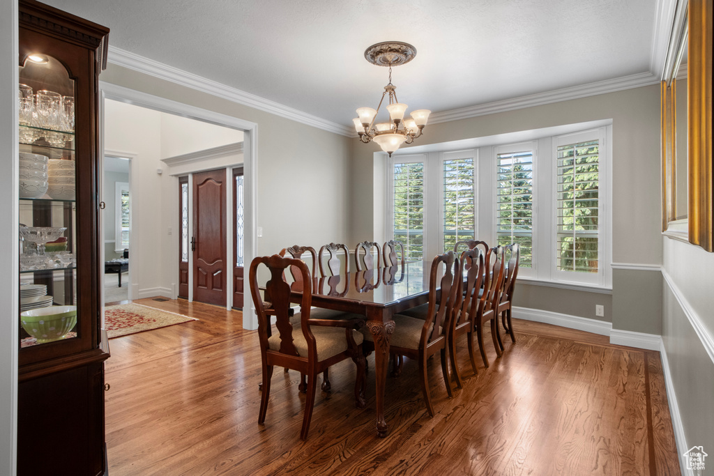 Dining room with an inviting chandelier, ornamental molding, baseboards, and wood finished floors