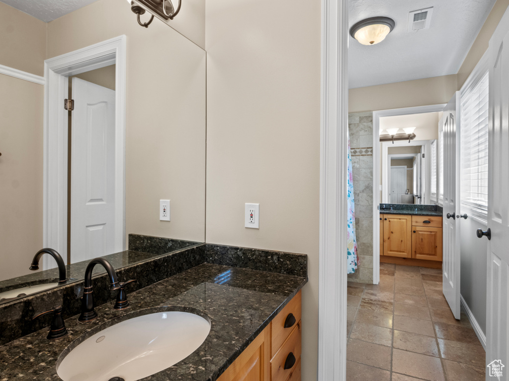 Full bath with visible vents, vanity, and stone tile floors