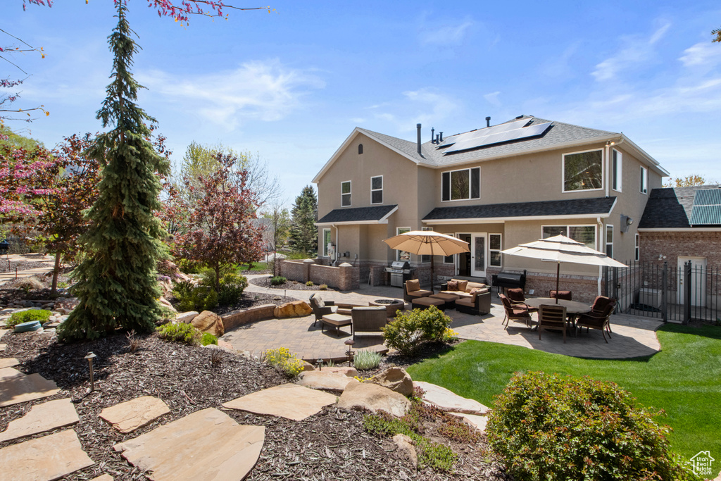 Rear view of house with fence, a patio, stucco siding, an outdoor living space, and solar panels