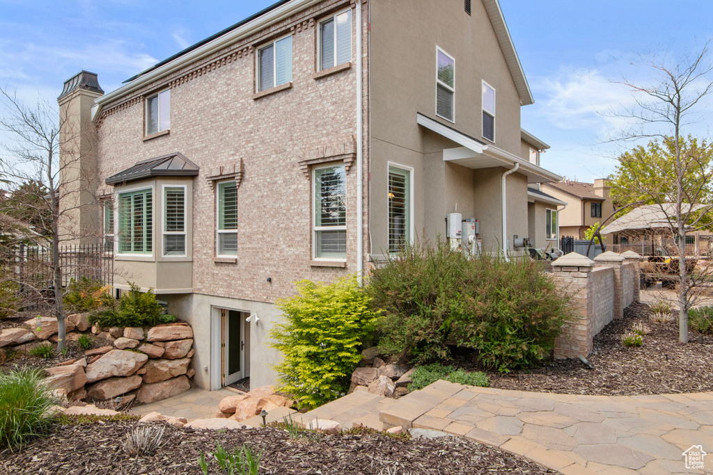 View of property exterior with a chimney, stucco siding, and fence