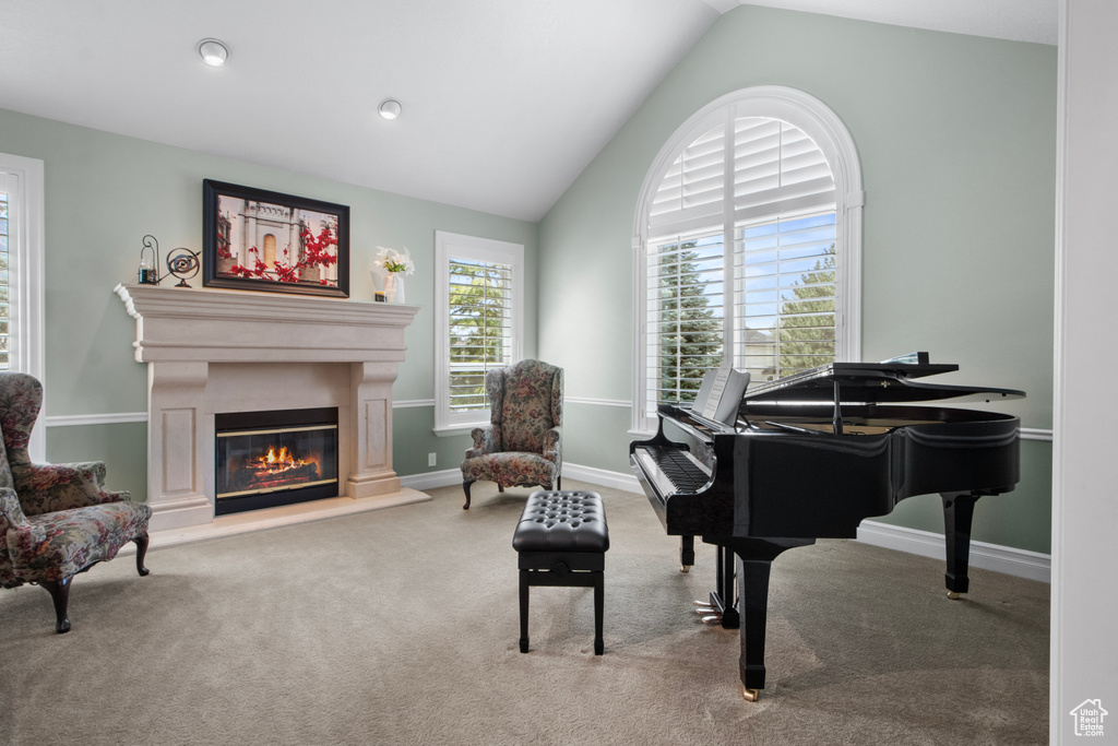 Living area featuring vaulted ceiling, carpet flooring, baseboards, and a glass covered fireplace