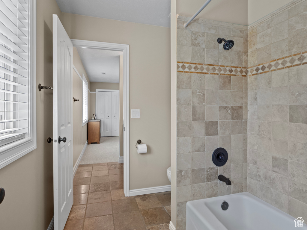 Full bath featuring baseboards, washtub / shower combination, and toilet
