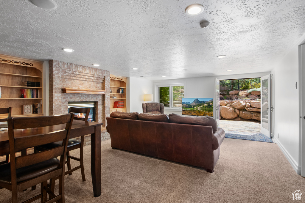 Living area with a textured ceiling, a fireplace, recessed lighting, and carpet floors