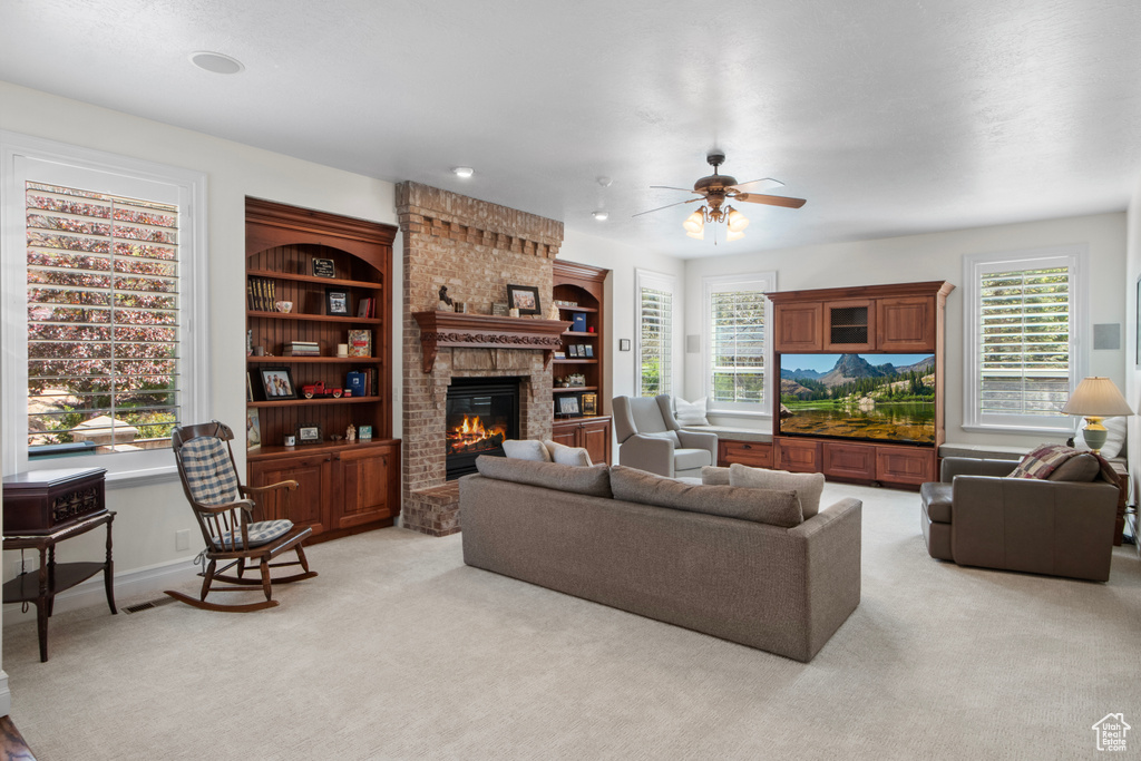 Living area featuring baseboards, a brick fireplace, ceiling fan, and light colored carpet