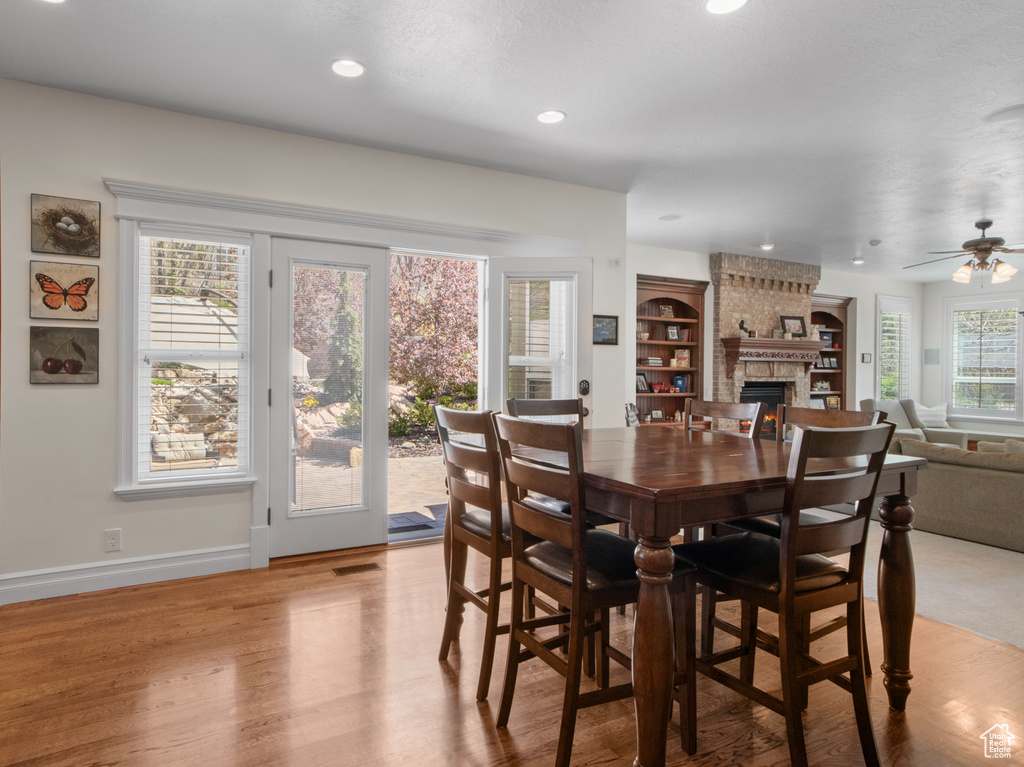 Dining area with a ceiling fan, recessed lighting, baseboards, light wood finished floors, and a large fireplace