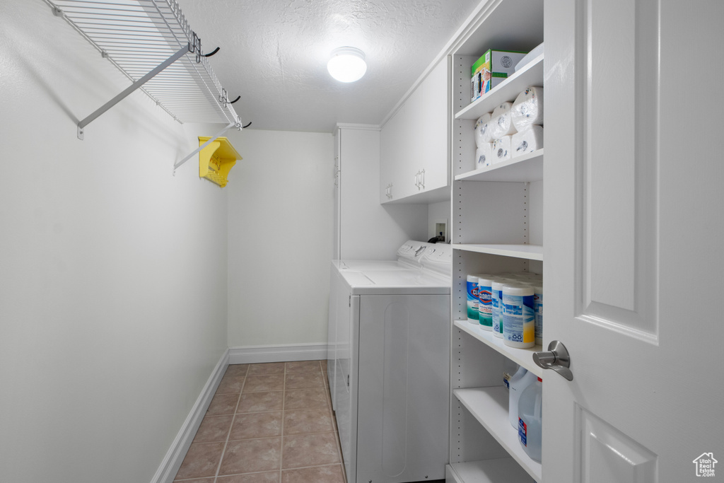 Laundry room featuring washing machine and clothes dryer, baseboards, light tile patterned floors, and cabinet space