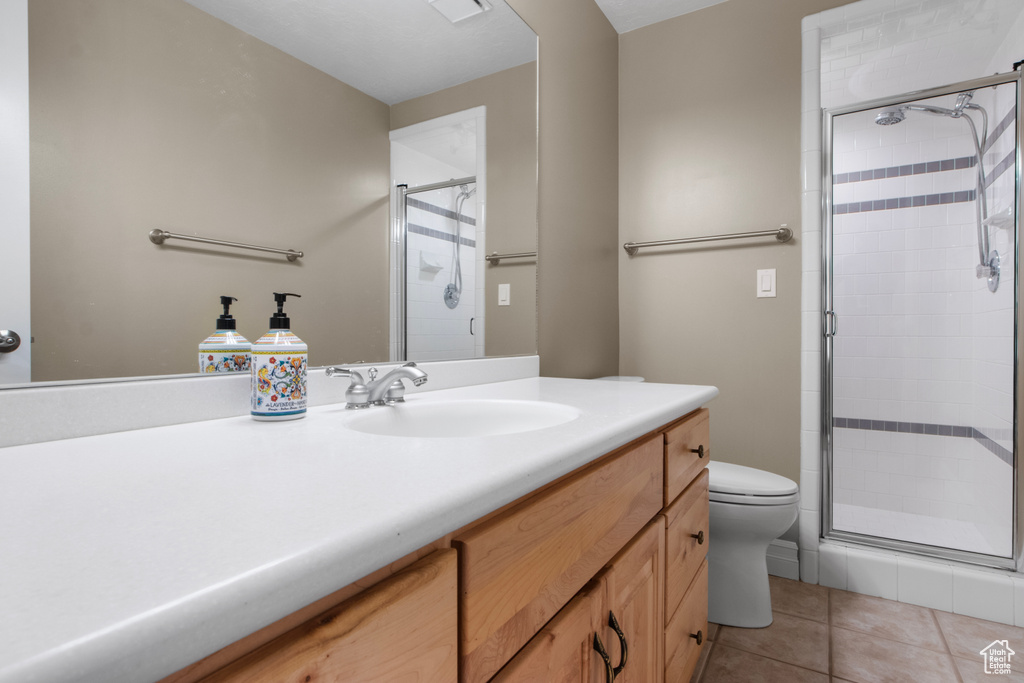 Bathroom featuring a stall shower, tile patterned floors, vanity, and toilet