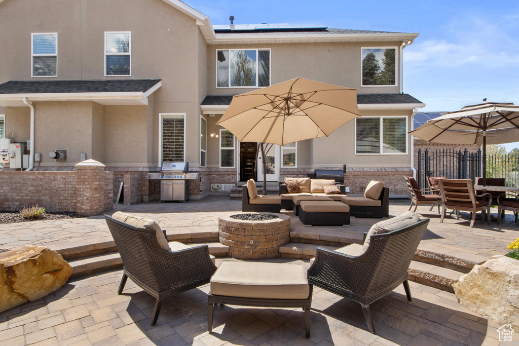 Back of property with an outdoor living space with a fire pit, a patio, area for grilling, and stucco siding