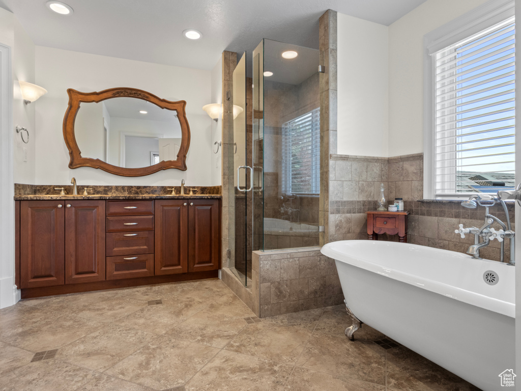 Full bath with a sink, a freestanding bath, a wealth of natural light, and a shower stall