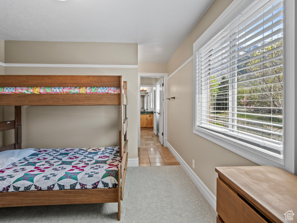 Bedroom with light colored carpet, baseboards, and light tile patterned flooring