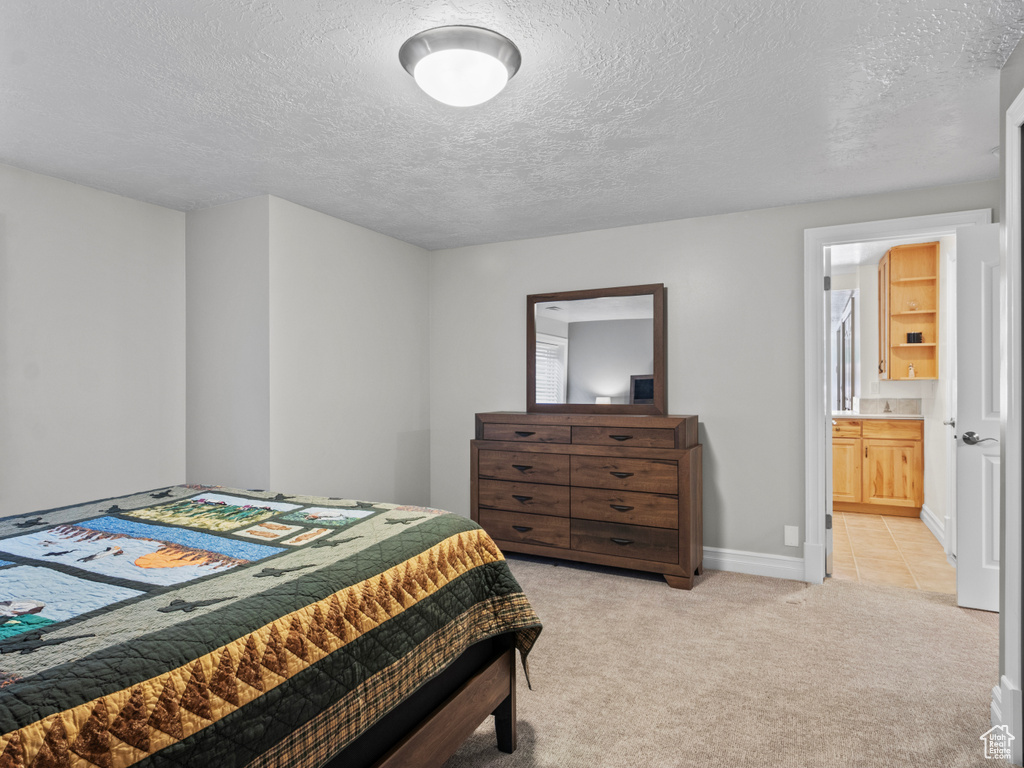 Bedroom featuring light carpet, a textured ceiling, and baseboards